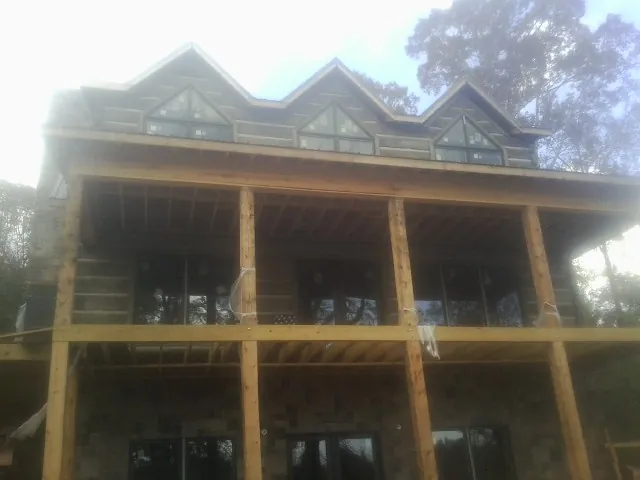 Dormers and porch framing on a large log home under construction — Roof Coating work by our crew in Opp