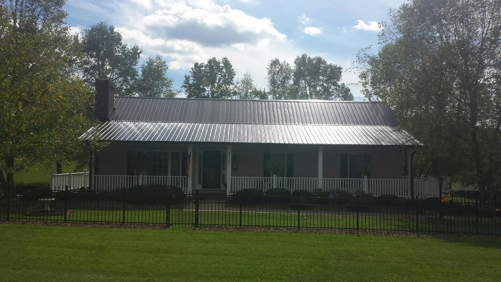 Gray metal roof on a brick ranch with a full width front porch — Gutter Guard Installation work by our crew in Opp