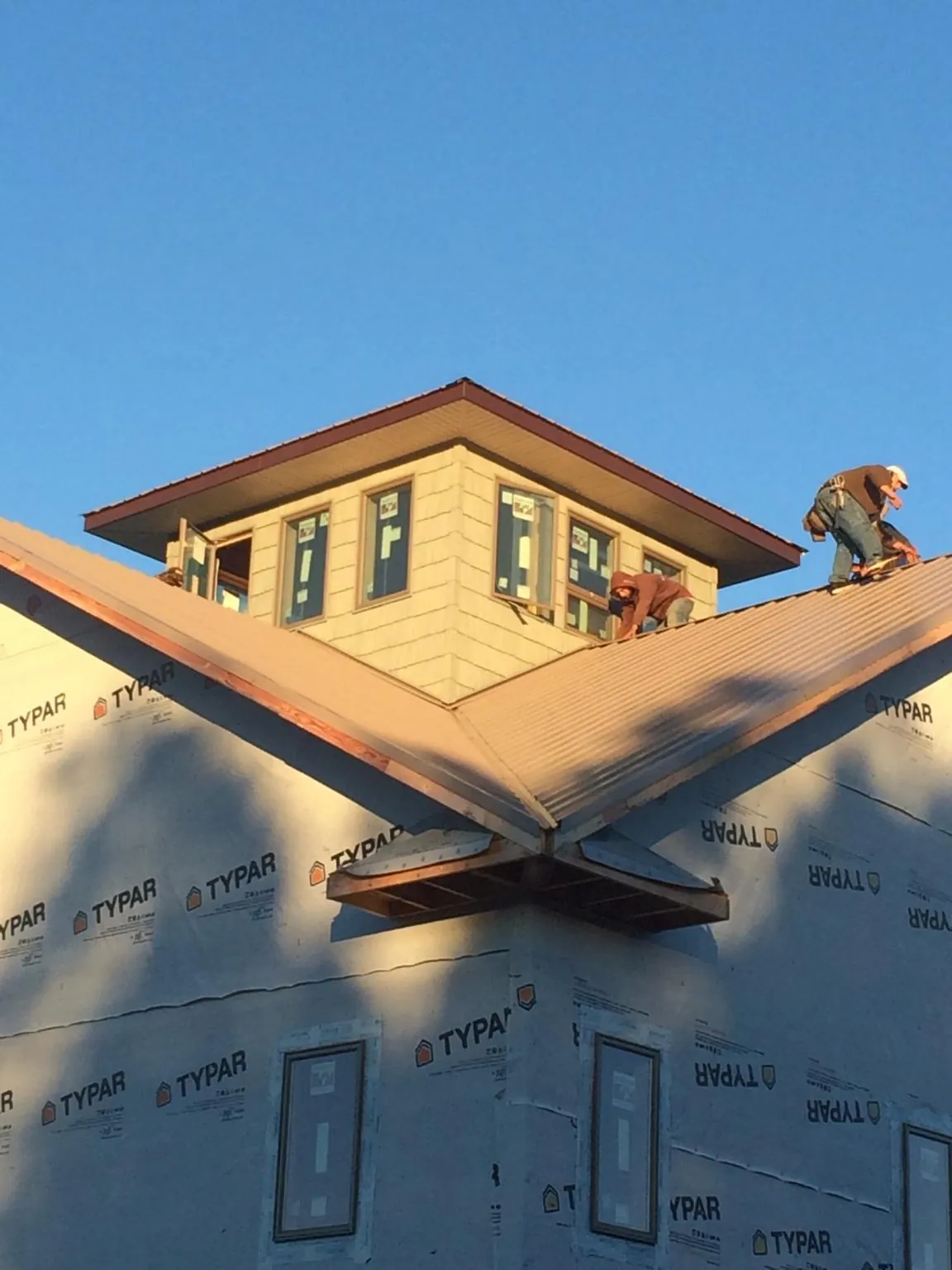 Roofers working around a rooftop cupola on a new metal roof at sunset — Roof Waterproofing in Opp by Roofing Brothers